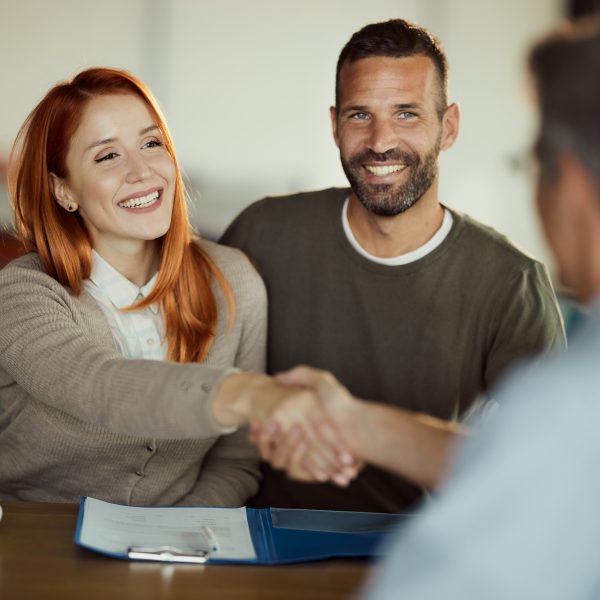 Happy couple came to an agreement with insurance agent in the office.