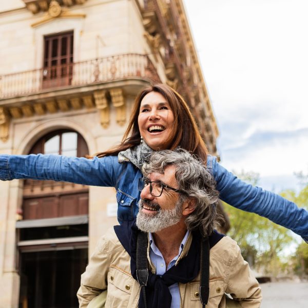 Joyful mature couple having fun together enjoying vacation on city street