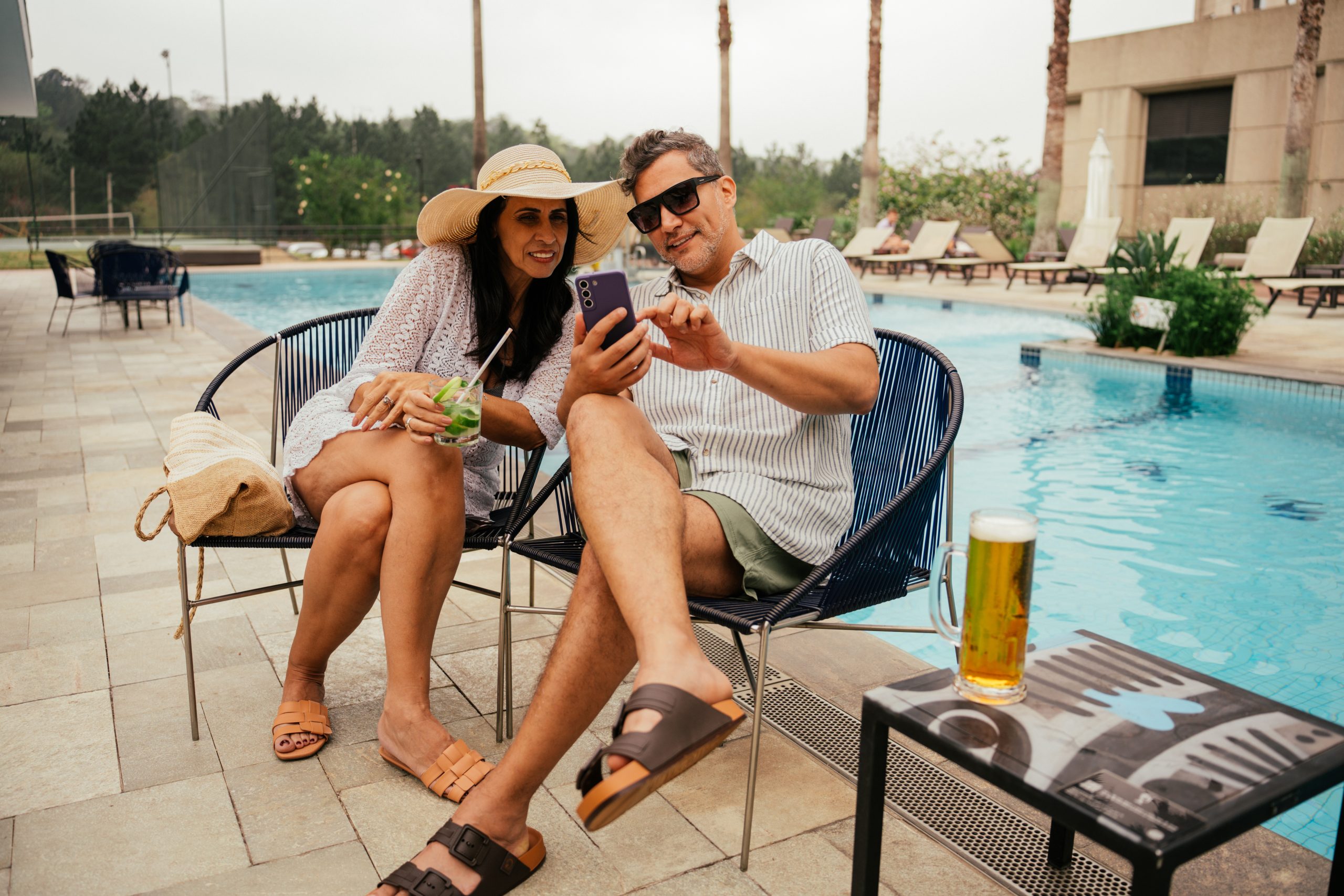 Mature couple using smartphone next to swimming pool
